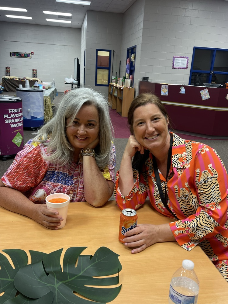 misery Tar is featured in a pink shirt with misery, Sutton and a leopard print dress. They are smiling together with their sunkist drinks and palm leaves are on the table.