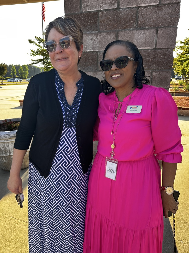 Two staff members standing outside smiling together .