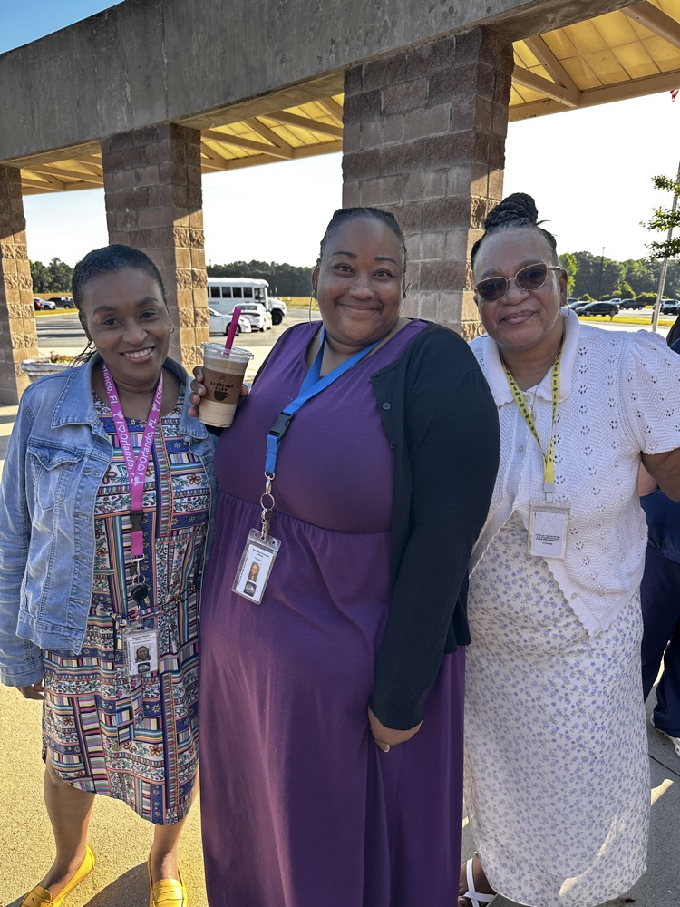 A groups of staff members stand together smiling outside.