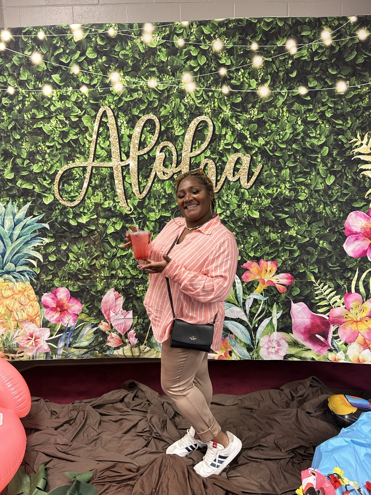teacher posing with their dirty sodas in front of the aloha Hawaiian backdrop