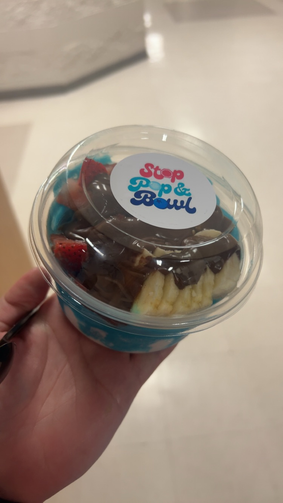A picture of frozen açai bowl that is blue and white with strawberries, banana, bananas, and Nutella on top