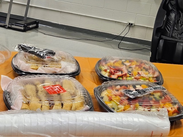 Fruit trays, sandwich trays, and stacked cups are displayed on a table prepared for Teacher Appreciation Week refreshments at ETMS.