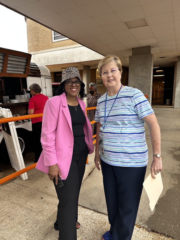 Two staff members pose together outside near the coffee trailer, smiling at the camera.