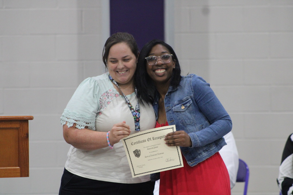 A student and teacher smile together while holding a certificate of recognition during West Bladen High School’s Scholastic Awards and Scholarship Night.