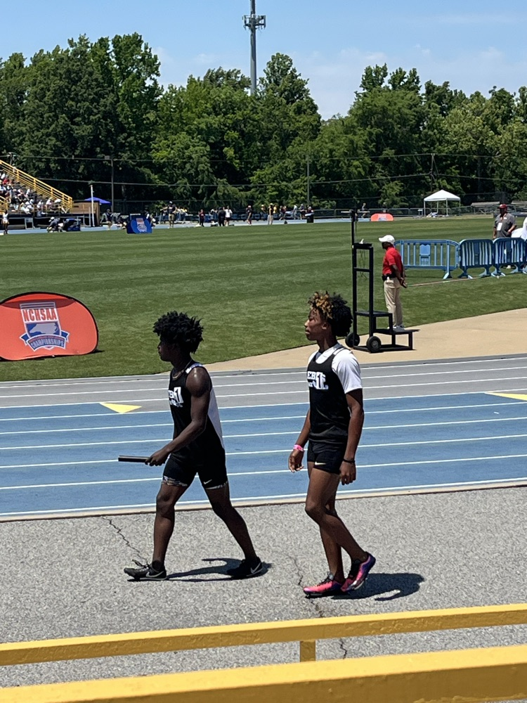 two students in track uniforms walking to an event