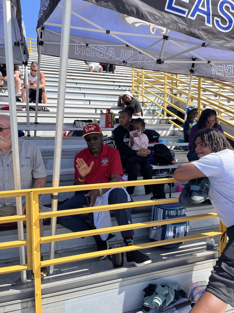 parents sit in the stand showing support for track athletes under a tent
