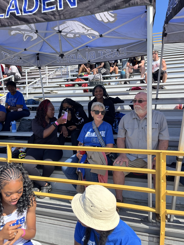 parents sit in the stand showing support for track athletes under a tent