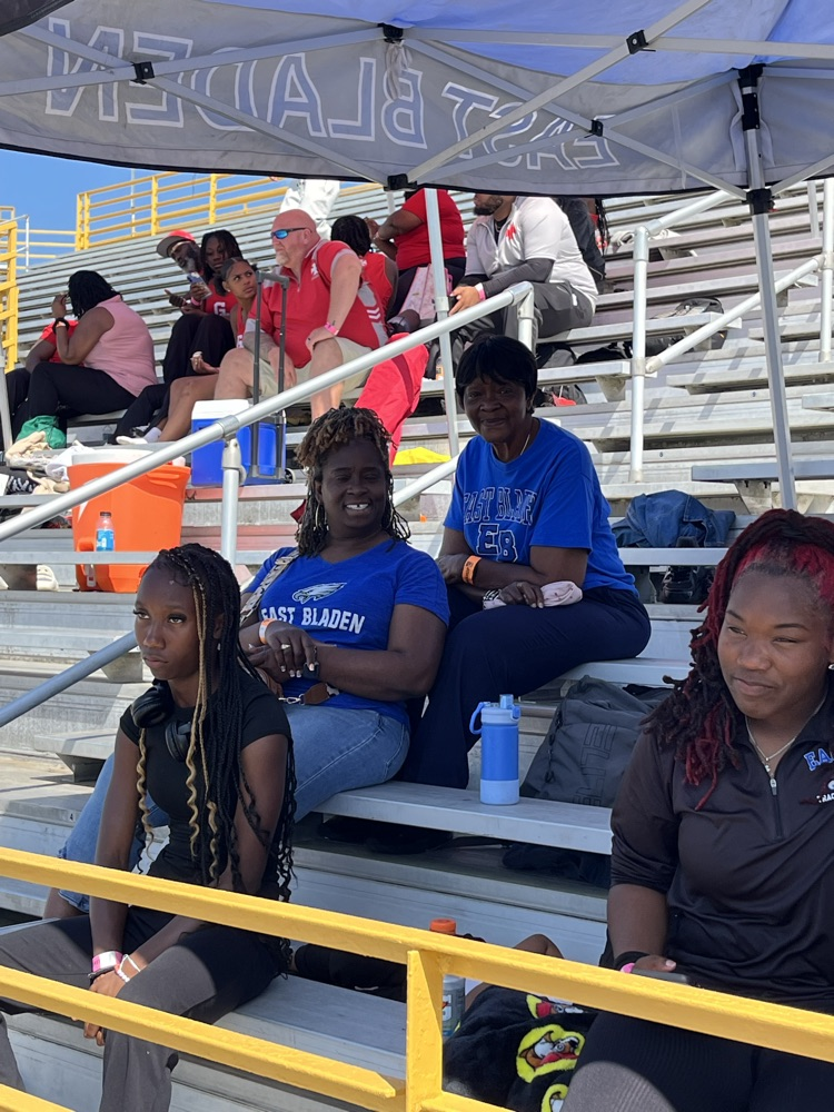 parents sit in the stand showing support for track athletes under a tent