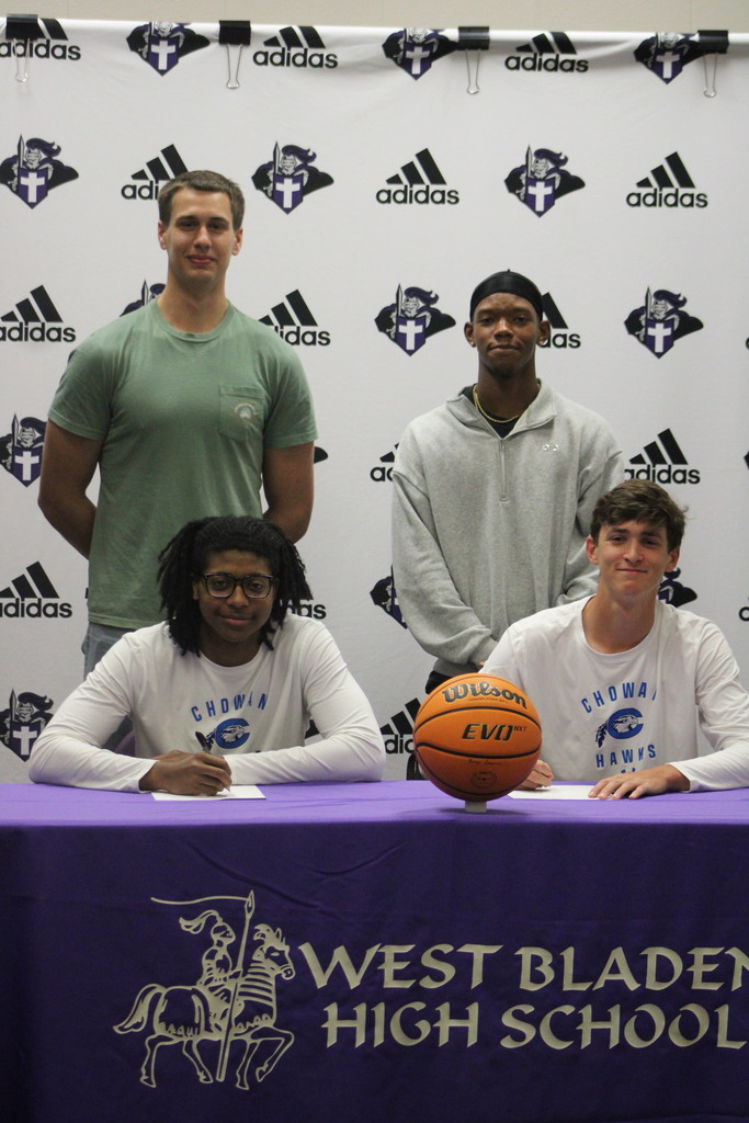 Jackson Pait and Tylik McCall pose with former teammates behind them after signing to continue their basketball careers at Chowan University during a ceremony at West Bladen High School.