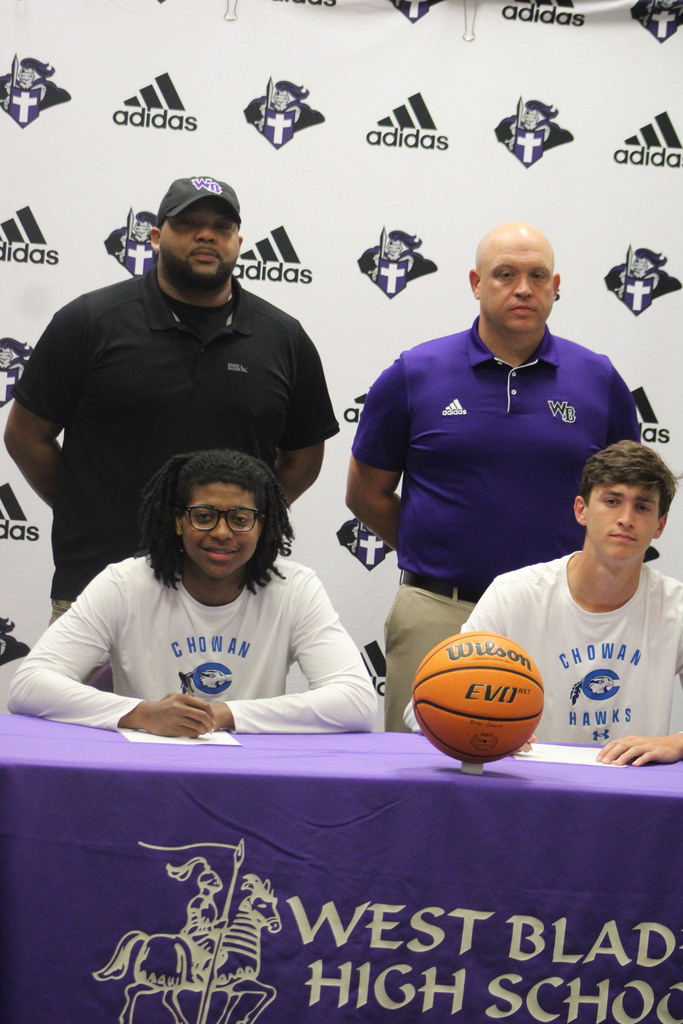 Jackson Pait and Tylik McCall sit at the signing table with coaches standing behind them during their Chowan University basketball signing ceremony.