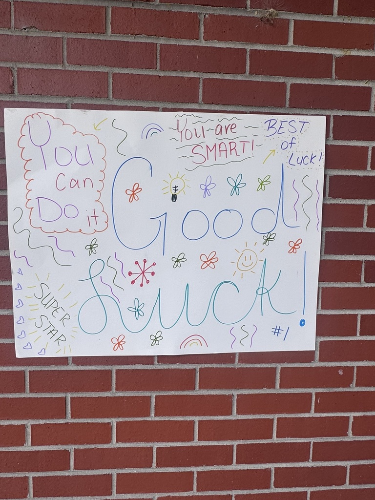 A bright and cheerful student-made poster hangs on a brick wall reading “Test Day You Are READY!” in rainbow-colored letters surrounded by stars, swirls, and encouraging notes for students taking the EOG test.