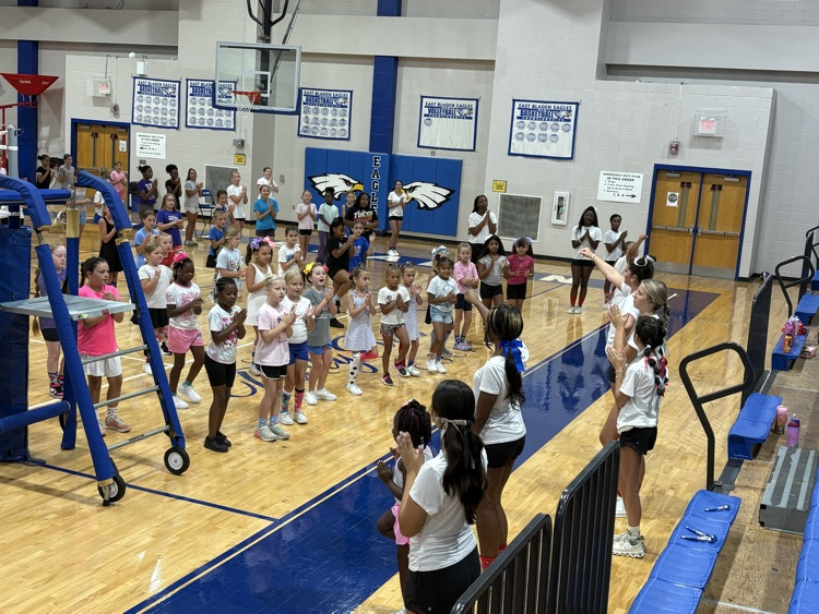 cheerleader showing the campers at cheer camp. Cheers in the gym.