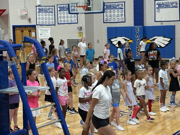cheerleader showing the campers at cheer camp. Cheers in the gym.