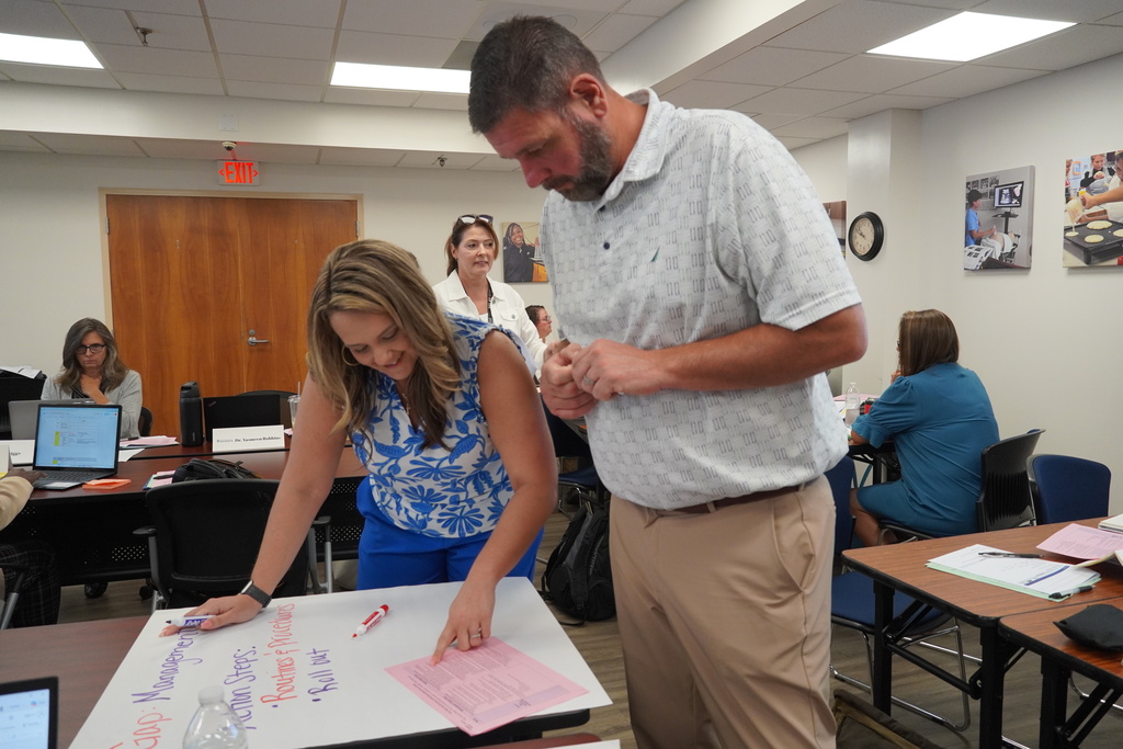 Two school administrators work collaboratively while writing on chart paper. 
