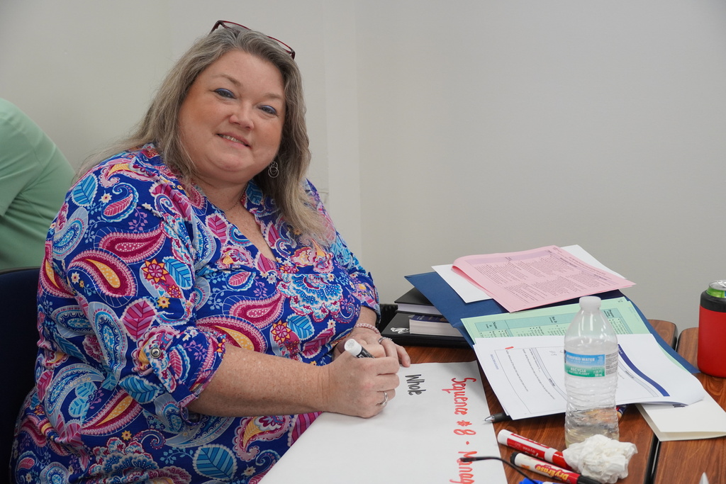 A school administrator sits smiling at a table. 