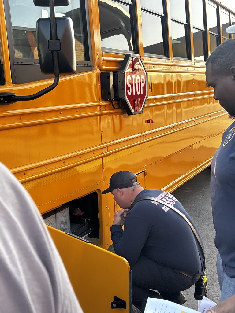 An adult is looking at the electrical panel on an electric school bus.
