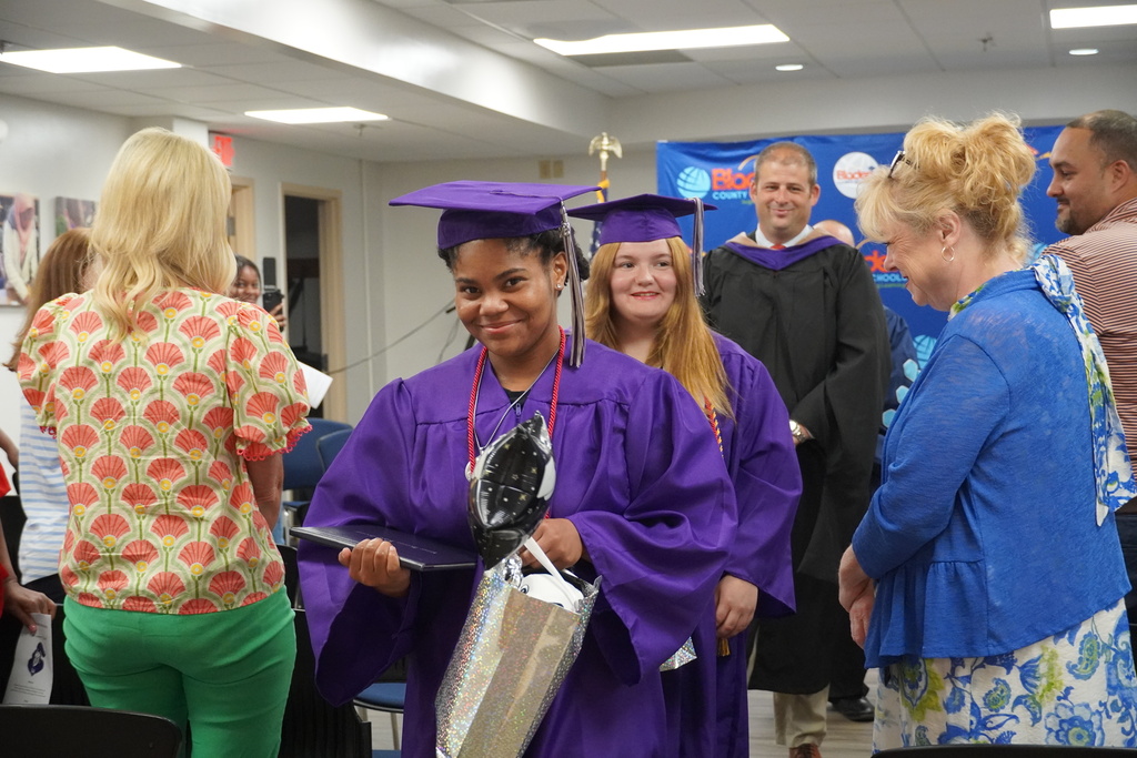 Graduates wearing purple caps and gowns are seen smiling as the process out of the ceremony.