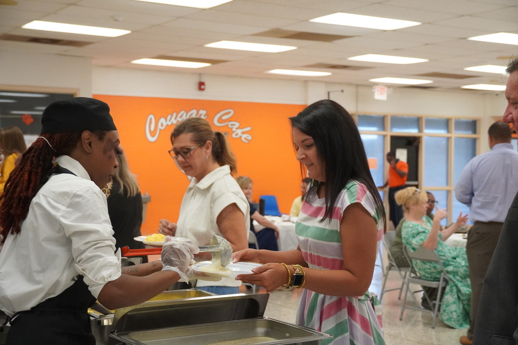 New employees stand in a buffet line to get breakfast.