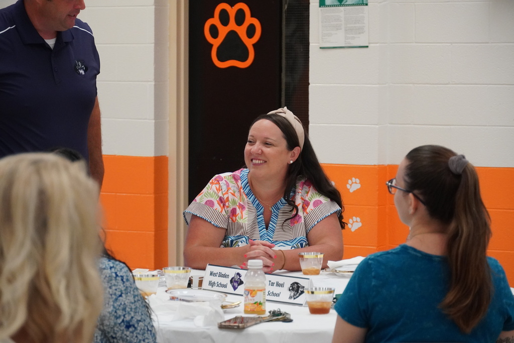 A new employee is sitting at a table smiling. 