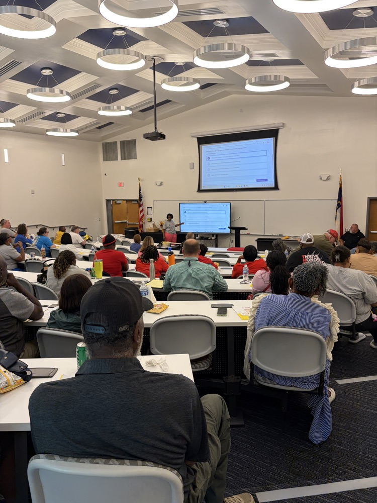A school nurse leads training for bus drivers in an auditorium .