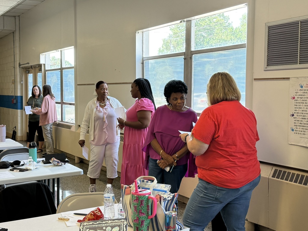 Staff members participate in a back-to-school meeting, working in small groups to discuss ideas, share information, and collaborate in preparation for the upcoming school year.