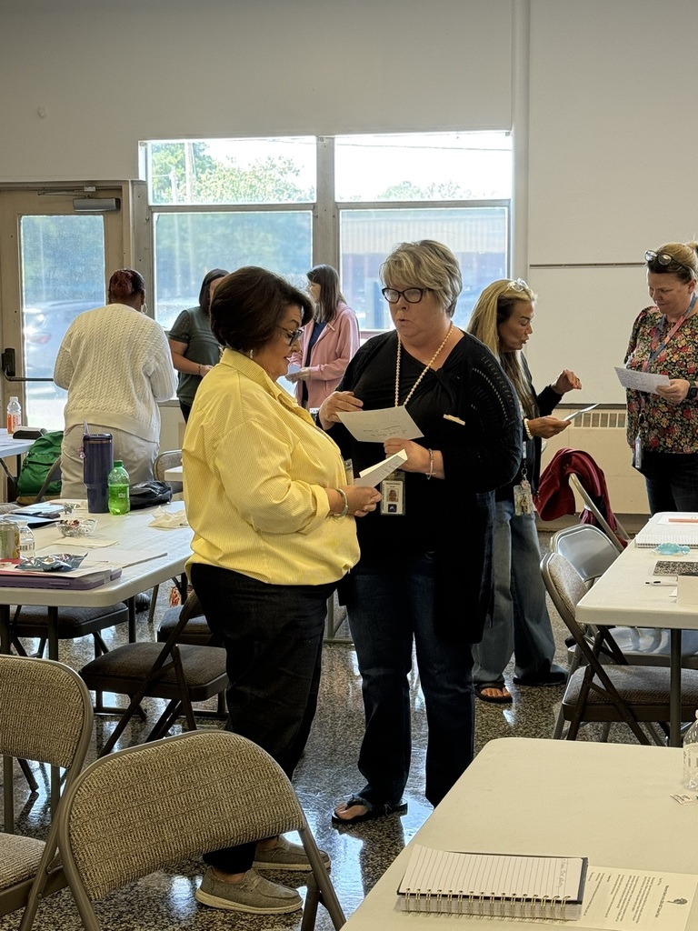 Staff members participate in a back-to-school meeting, working in small groups to discuss ideas, share information, and collaborate in preparation for the upcoming school year.