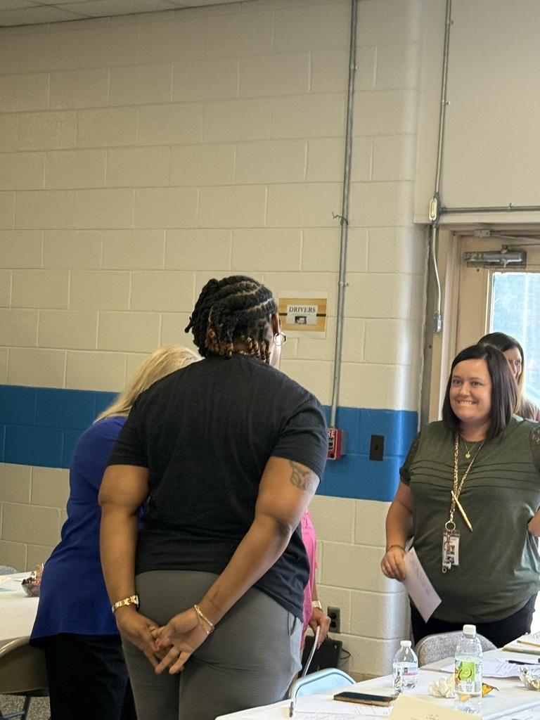 Staff members participate in a back-to-school meeting, working in small groups to discuss ideas, share information, and collaborate in preparation for the upcoming school year.