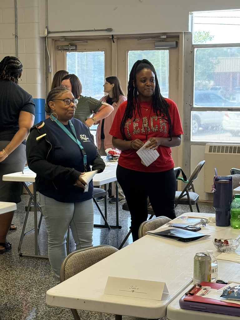 Staff members participate in a back-to-school meeting, working in small groups to discuss ideas, share information, and collaborate in preparation for the upcoming school year.