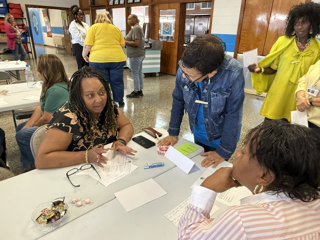 Staff members participate in a back-to-school meeting, working in small groups to discuss ideas, share information, and collaborate in preparation for the upcoming school year.
