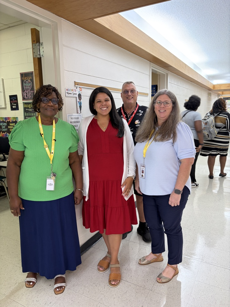 A group of educators stand smiling together in a classroom doorway.
