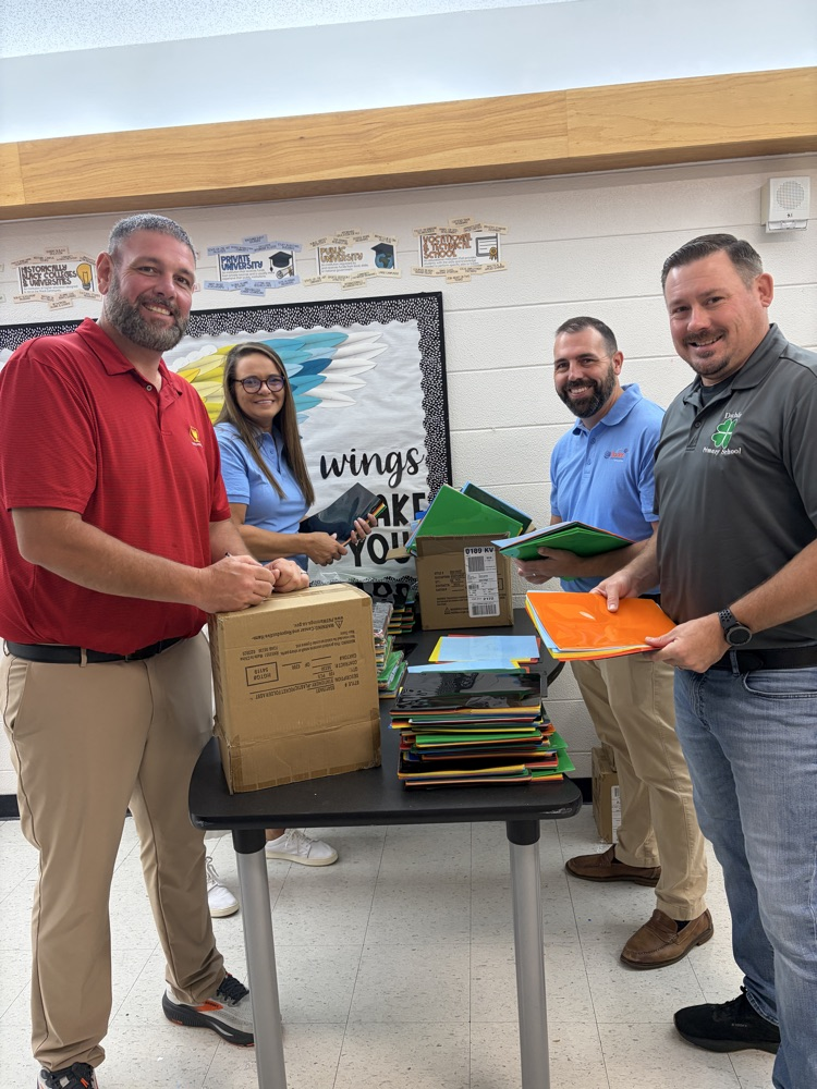 4 staff members stand around a table organizing folders.