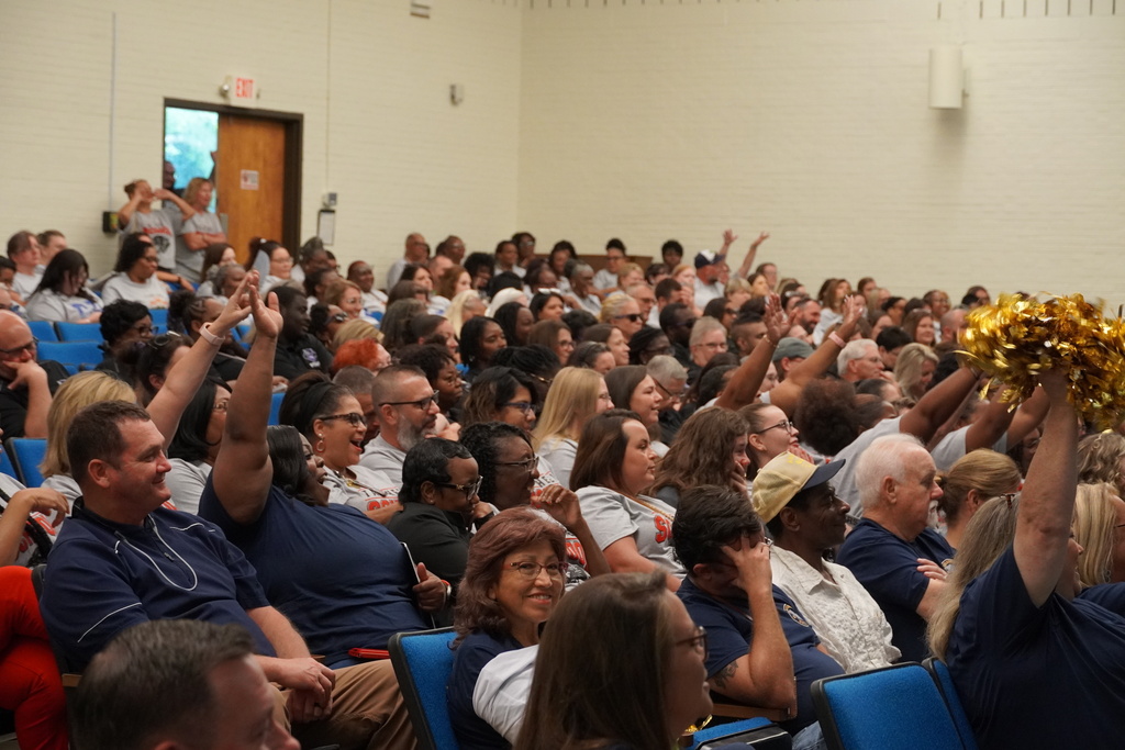 Employees are seen smiling and cheering together in the auditorium. 