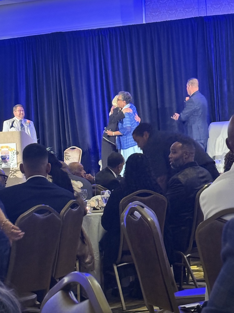Coach Evers being recognized on stage at awards ceremony .
