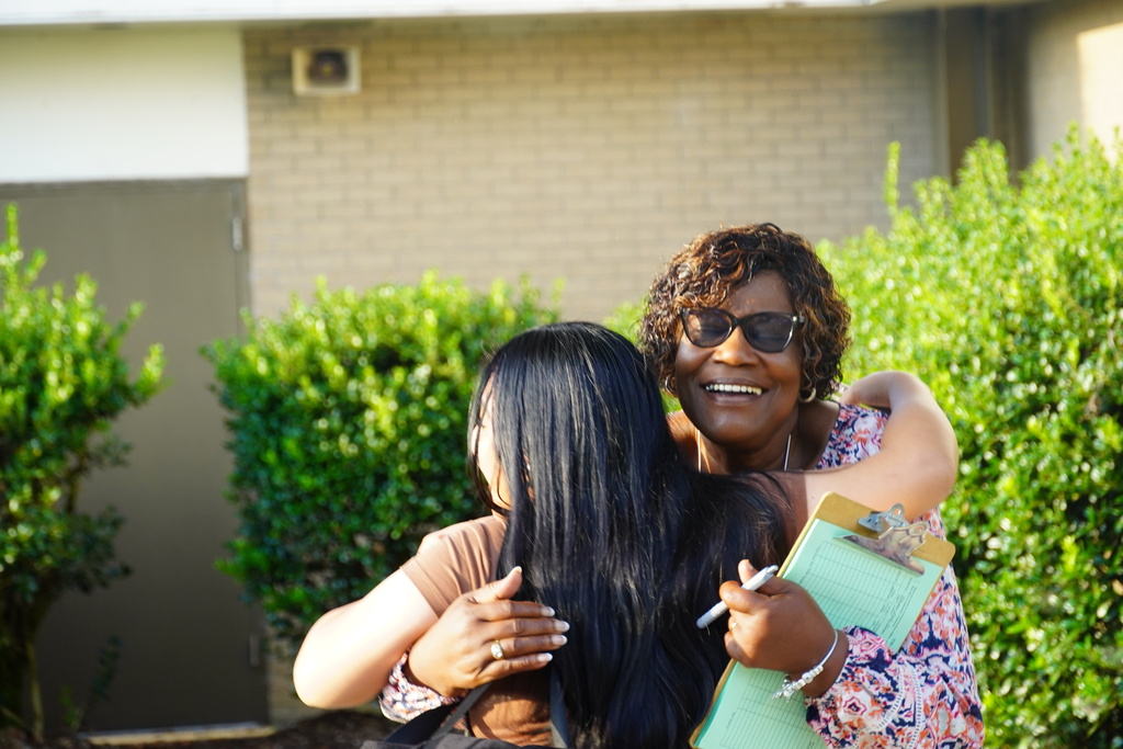 A Bladen Early College staff member greets a student with a smile and hug.