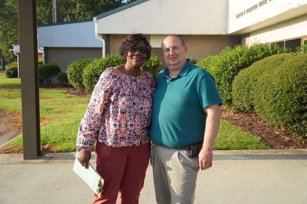 Bladen Early College staff member and the district's superintendent stand smiling outside of the school building.