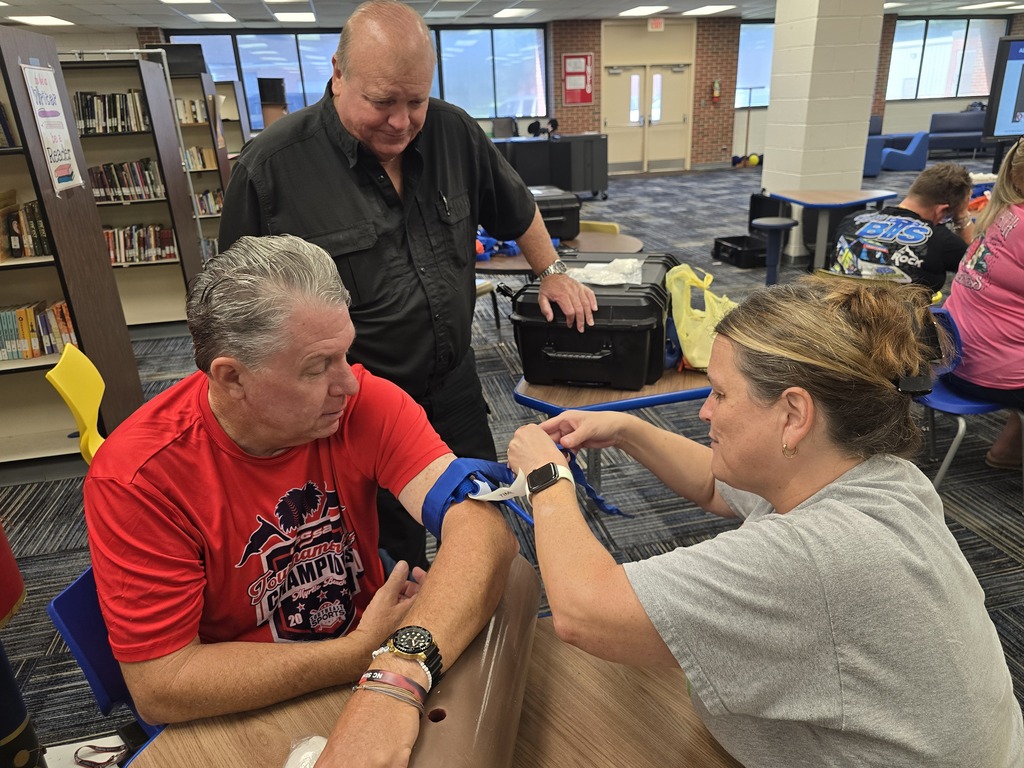 Alt text: BMS staff members practice applying a tourniquet during Stop the Bleed training while an instructor observes and provides guidance.