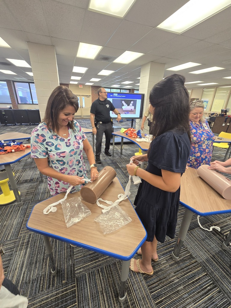BMS staff members practice wound-packing techniques on training models during Stop the Bleed training as an instructor provides guidance.