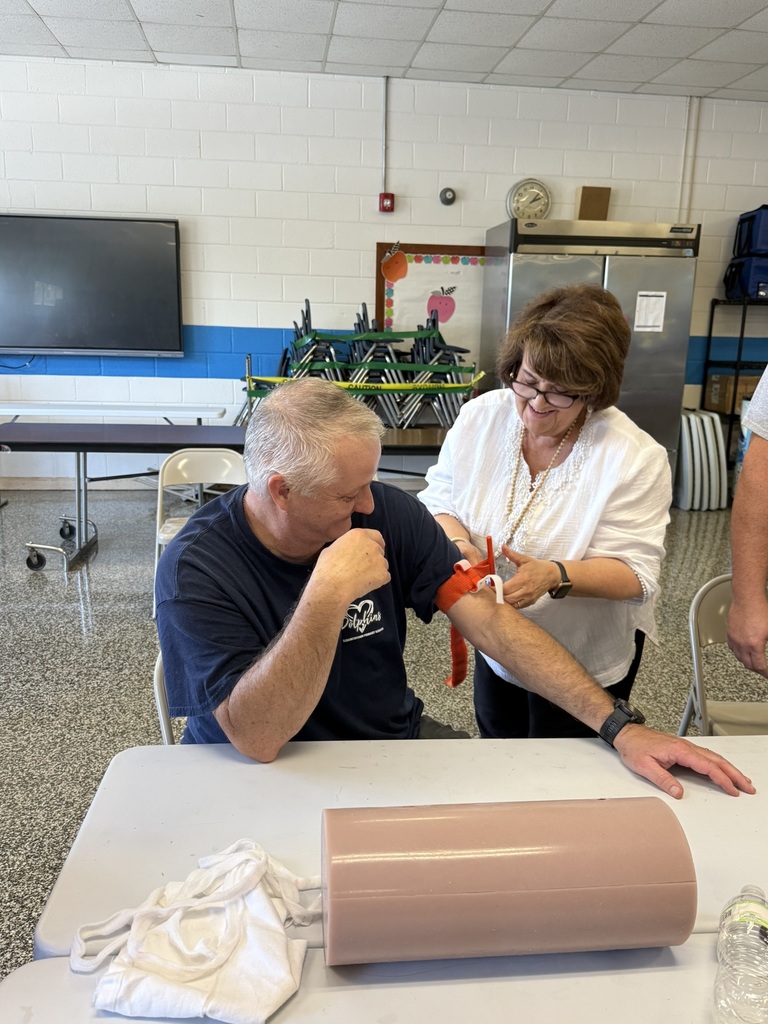 An EPS staff member practices applying a tourniquet to a colleague’s arm during Stop the Bleed emergency response training.
