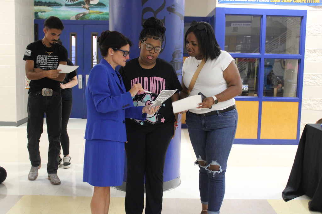 An East Bladen High School administrator is helping a student and guardian while reviewing paperwork.