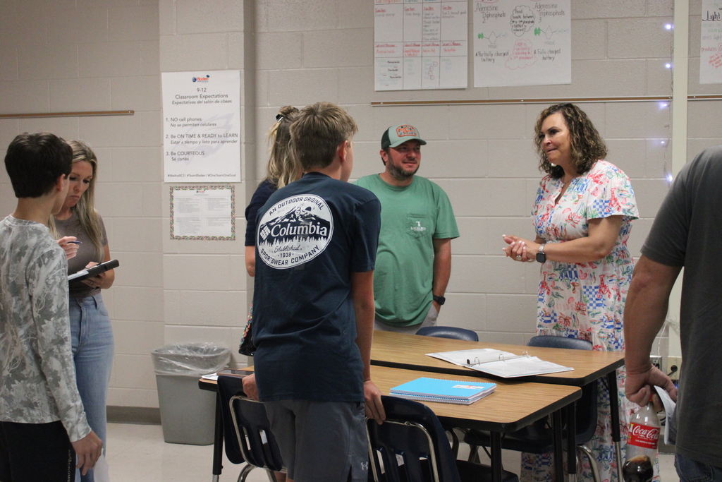 An East Bladen High School teacher is speaking with students and parents in a classroom.