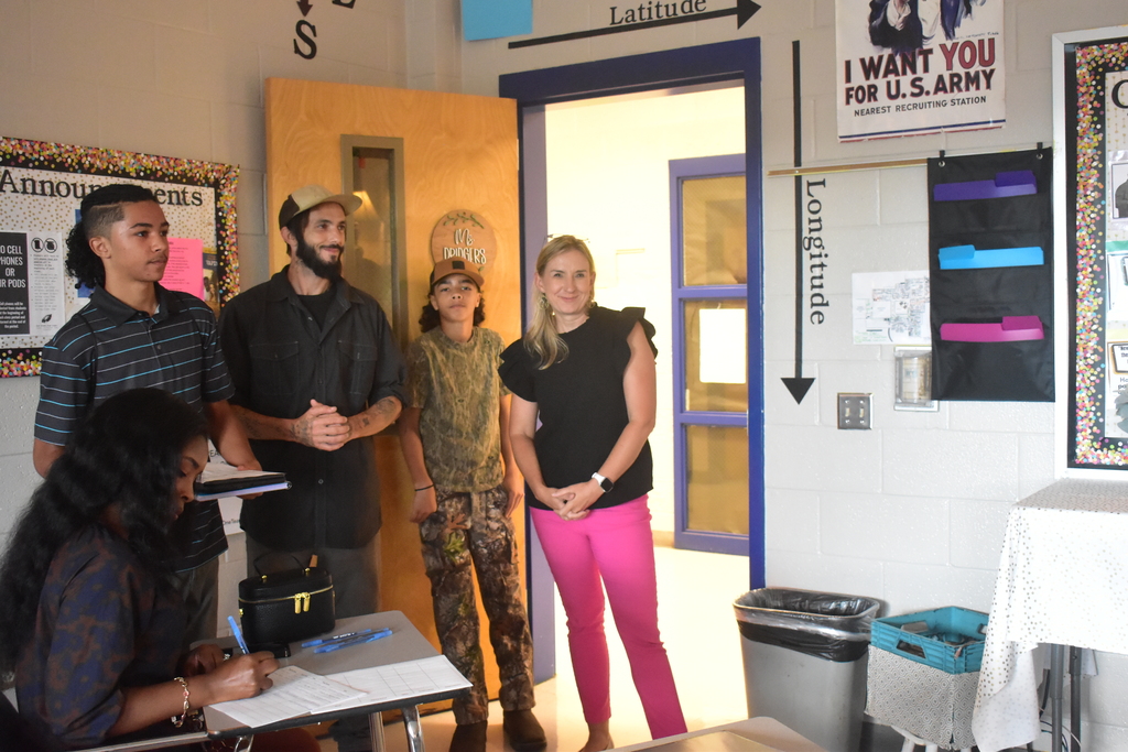An East Bladen High School teacher stands smiling in a doorway, welcoming students and parents. 