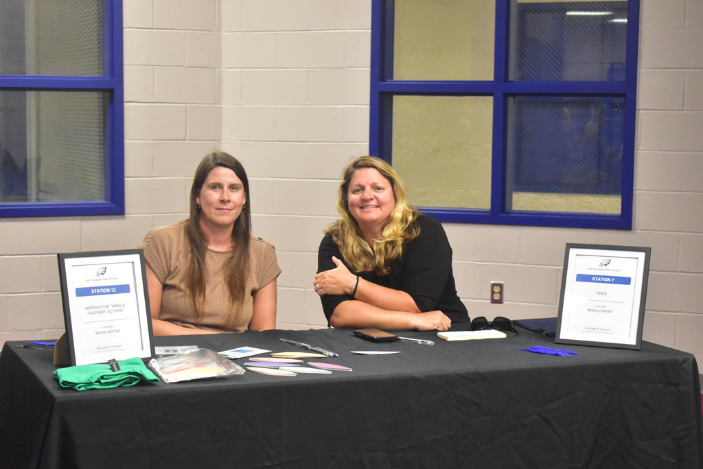 Two East Bladen High School staff members sit smiling behind a table. 