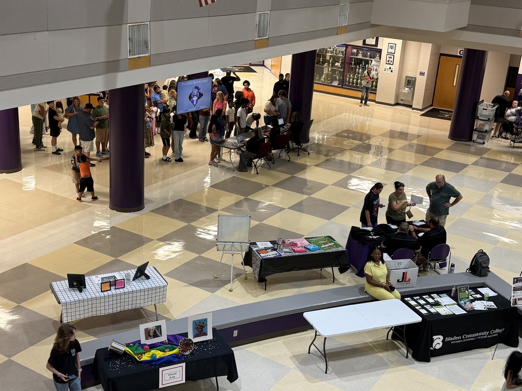 An elevated view of a crowded school lobby with students and parents visiting informational tables during orientation.