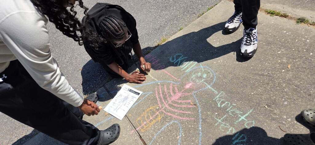 Students are doing school work outside with chalk.