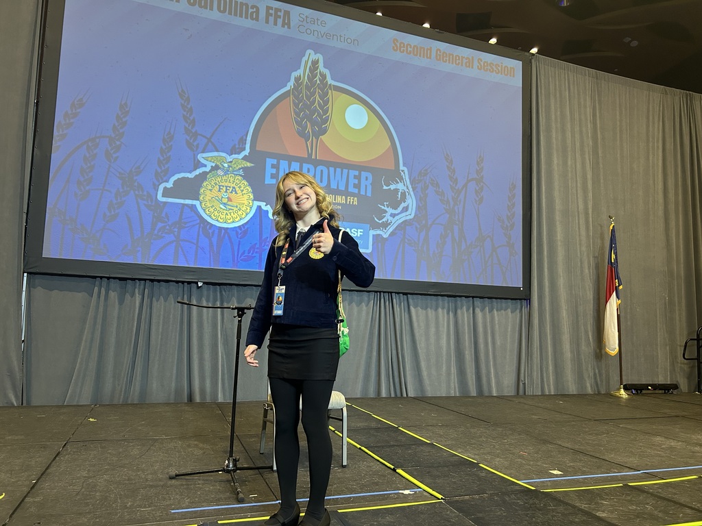 Student giving a thumbs up on stage.