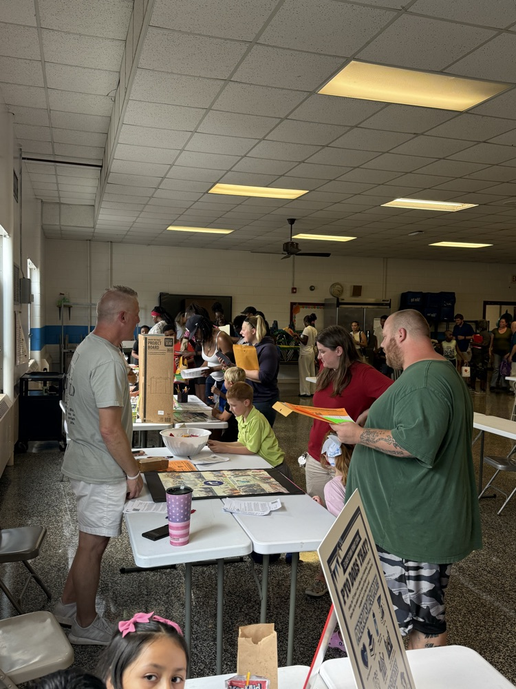     Families visit information tables and talk with staff members inside the cafeteria during Elizabethtown Primary School’s Open House.