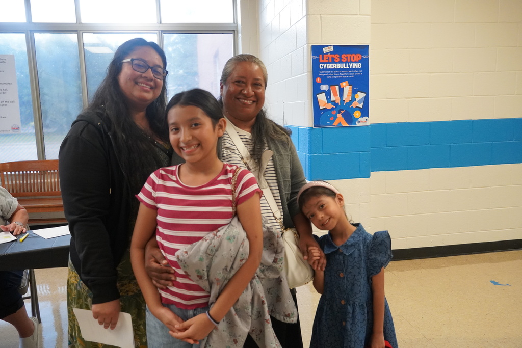 A family is smiling together in the school hallway.