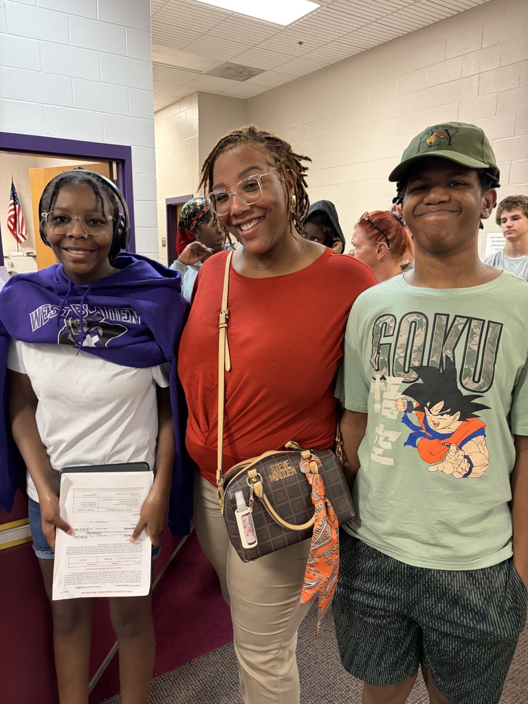 A mom and two students stand smiling in line at open house.