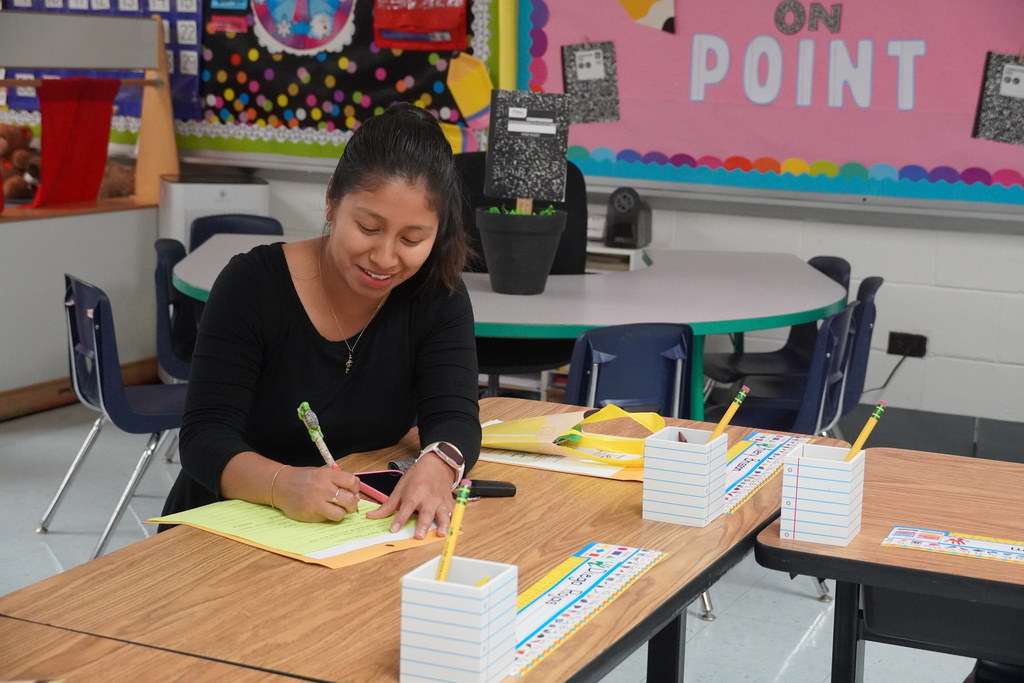 A parent is sitting at a desk completing paperwork.