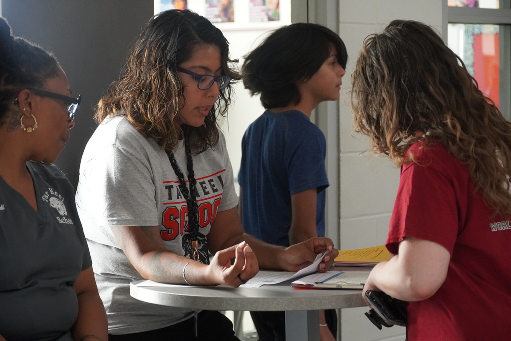 A teacher is talking with a parent at a tall table. 